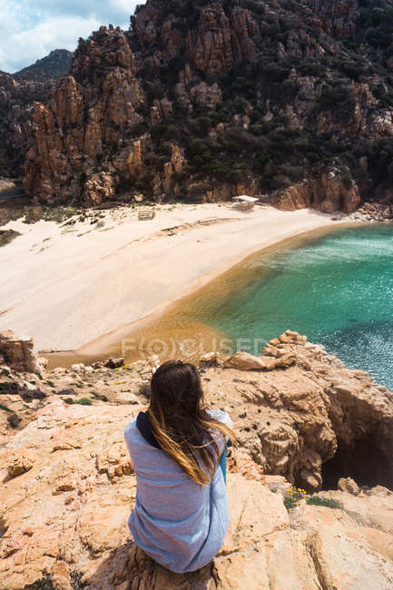 Woman sitting on rocks at seaside and looking at view — Stock Photo