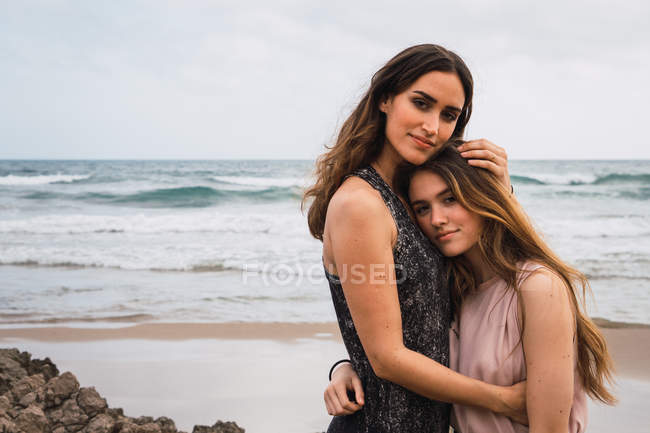 Портрет усміхненої жінки і дівчини-підлітка, що стоїть на пляжі — стокове фото