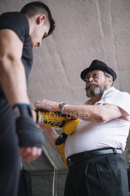 Erwachsenentrainer bindet Boxerhandschuh an die Hand des Sportlers im Ring. — Stockfoto