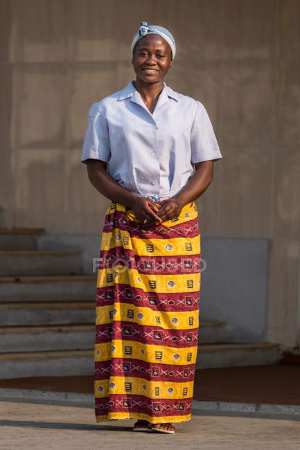 ANGOLA - ÁFRICA - 5 de abril de 2018 - mujer negra con tocado azul y falda estampada mirando a la cámara - foto de stock