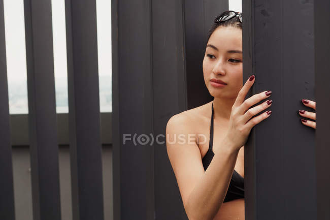 Mujer reflexiva en traje de baño apoyado en la pared - foto de stock