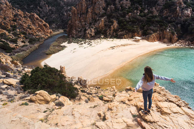 Femme debout sur des rochers au bord de la mer et regardant la vue — Photo de stock