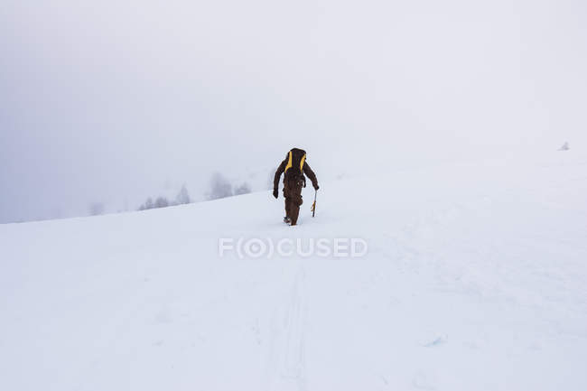 Tourist with backpack climbing on snowy mountain — Stock Photo