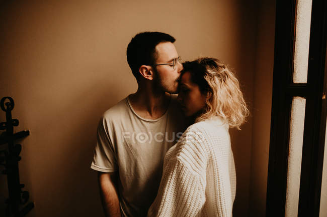 Pareja romántica abrazándose delante de la pared en casa - foto de stock