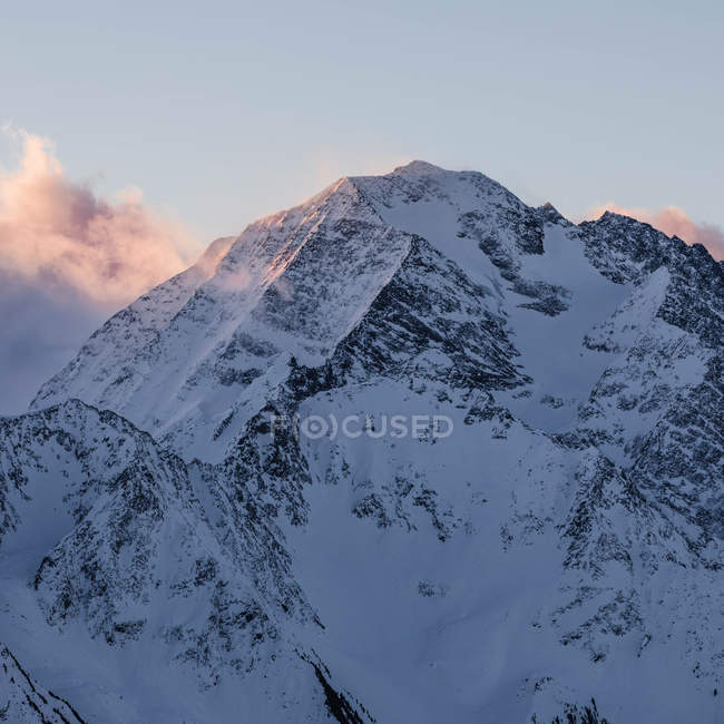 Pico de alta montaña cubierto de nieve a la luz del día - foto de stock
