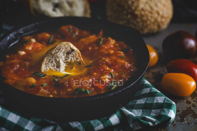 Жареное яйцо с помидорами, красным перцем и хлебом в сковороде — стоковое фото