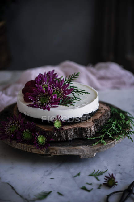 Bolo gostoso decorado com flores frescas em bandeja de madeira — Fotografia de Stock