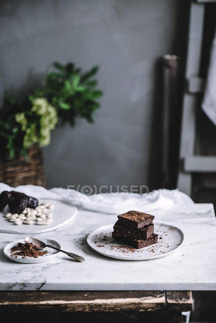 Pieces of tasty brownie on plate on white marble surface — Stock Photo