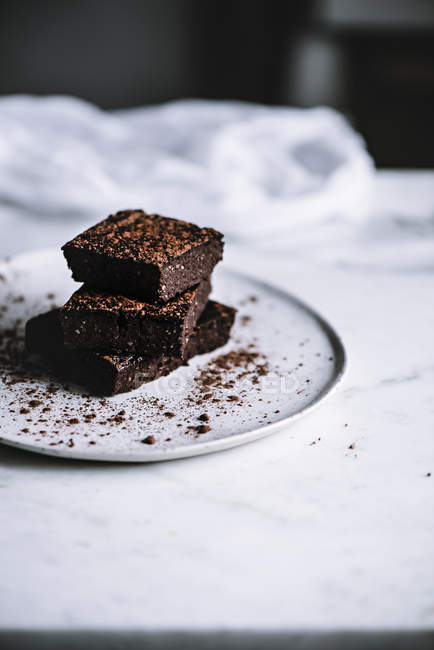 Pedaços de brownie saboroso na placa na superfície de mármore branco — Fotografia de Stock