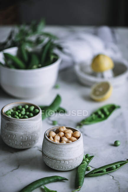 Primo piano di vasetti pieni di piselli maturi in piedi su un tavolo di marmo bianco — Foto stock