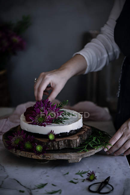 Nahaufnahme einer Frau, die ausgefallenen Kuchen mit Blumen dekoriert — Stockfoto