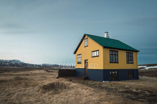Imagen exterior de colorida casa situada sola en llanura de montañas frías en Islandia. - foto de stock