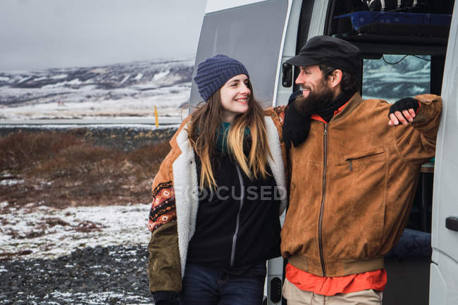 Cheerful couple leaning on van in nature — Stock Photo