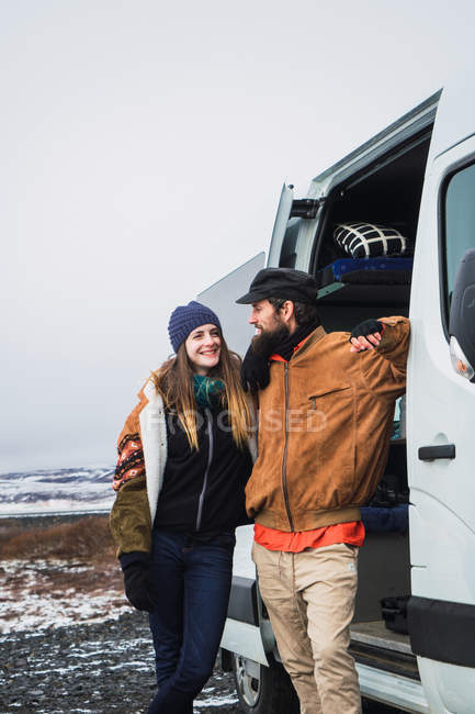 Cheerful couple leaning on van in nature — Stock Photo