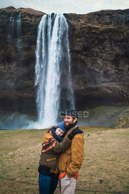 Couple debout devant la cascade ensemble — Photo de stock