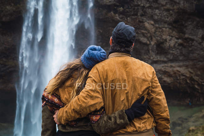 Paar steht gemeinsam vor Wasserfall — Stockfoto