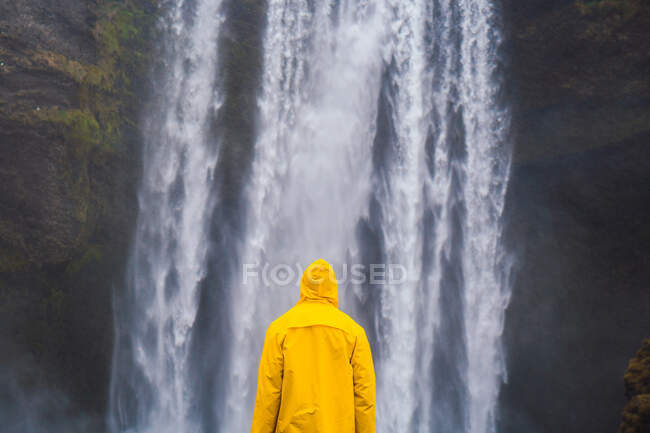 Uomo in piedi vicino alla cascata — Foto stock