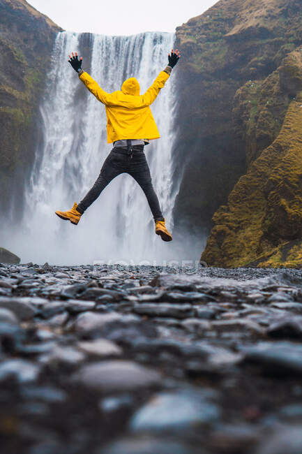 Uomo che salta vicino alla cascata — Foto stock