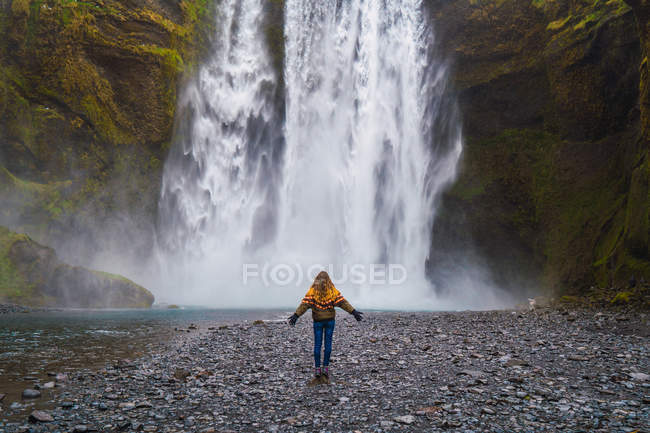 Жінка в теплому одязі, що стоїть біля водоспаду — стокове фото
