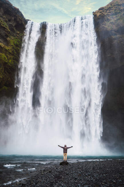 Людина стоїть біля водоспаду — стокове фото
