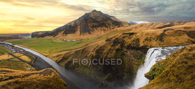 Wunderschöne Landschaft mit Textur Bergen und Wasserfall unter bewölktem Himmel, Island — Stockfoto