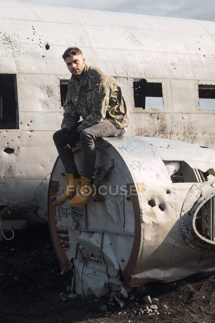 Homem sentado no velho avião destruído — Fotografia de Stock