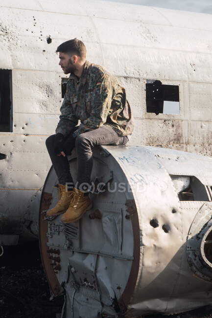 Man sitting on old destroyed airplane — Stock Photo