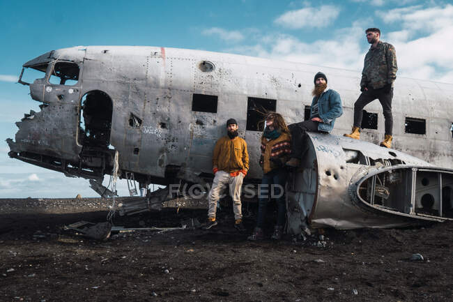 Группа молодых бородатых мужчин и женщин в теплой одежде позируют на разбившихся самолетах в пустыне — стоковое фото
