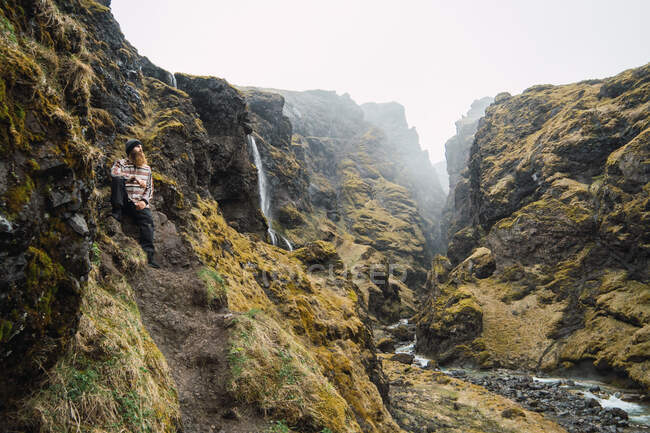 Человек, сидящий в красивой скалистой местности — стоковое фото