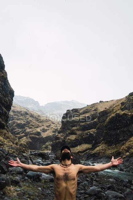 Shirtless ma standing under rain in mountains — Stock Photo