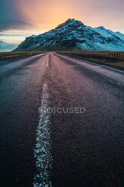 Дорога в сільській місцевості і засніжена гора на сході сонця — стокове фото