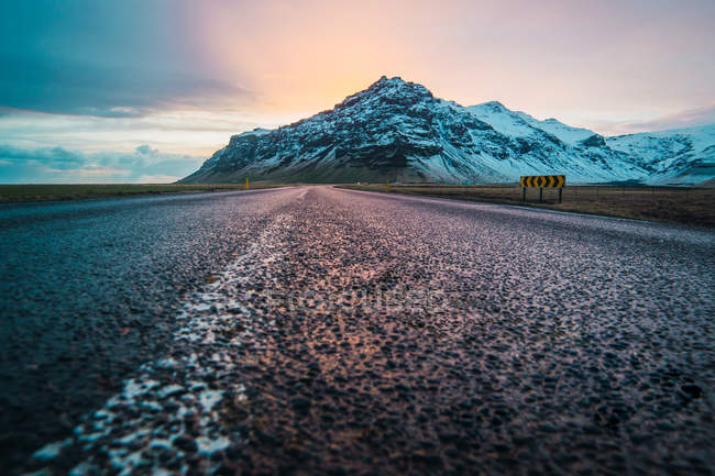Estrada no campo e montanha nevada ao nascer do sol — Fotografia de Stock
