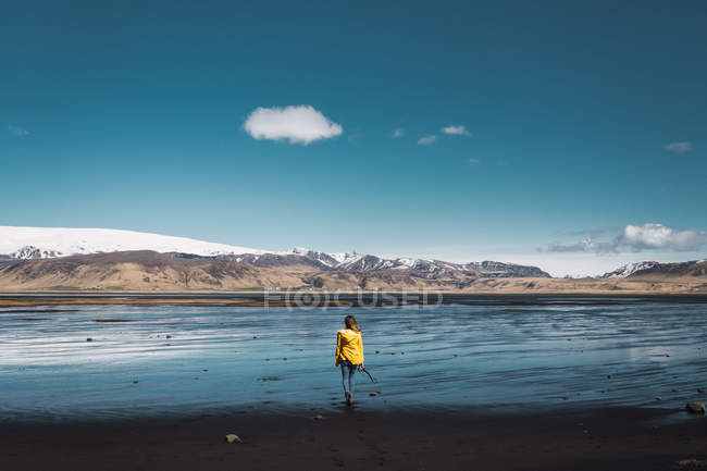 Woman in yellow jacket standing next mountain landscape — Stock Photo
