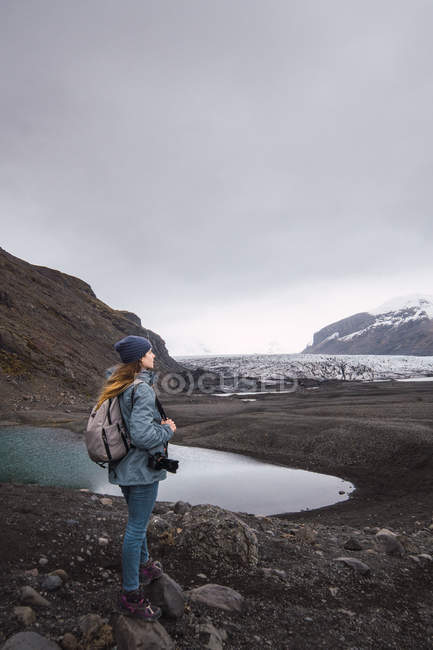 Woman with camera and backpack enjoying snowy mountains view — Stock Photo