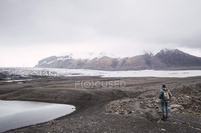 Mulher com mochila de pé e desfrutando de vista de montanhas nevadas — Fotografia de Stock
