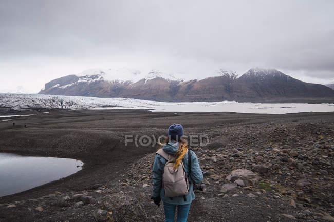 Frau mit Rucksack steht und genießt verschneiten Bergblick — Stockfoto