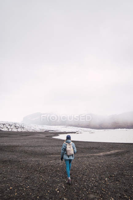 Donna con zaino a piedi sulla costa invernale — Foto stock