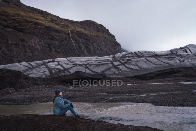 Mulher sentada na frente de falésias e desfrutando de vista — Fotografia de Stock