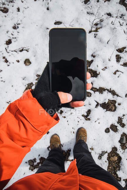 Vue de la récolte d'en haut de la personne tenant smartphone à l'extérieur portant des vêtements d'hiver — Photo de stock