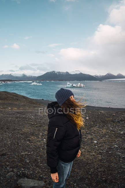 Female tourist standing on cold seascape and looking at view — Stock Photo