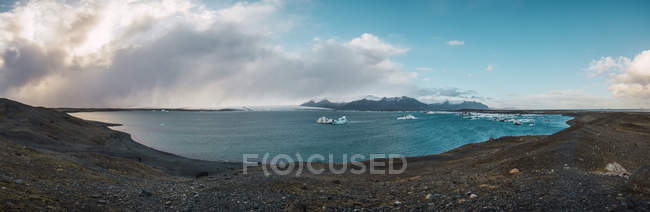 Vista panorâmica da costa com montanhas cobertas de neve no fundo, Islândia — Fotografia de Stock