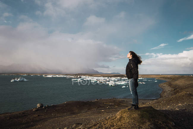 Femme debout sur le paysage marin froid et regardant la vue — Photo de stock