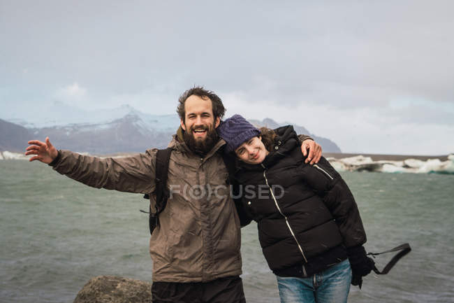 Laughing couple standing at cold lake in nature — Stock Photo