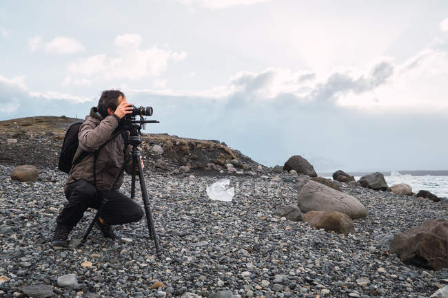 Uomo che imposta attrezzature fotografiche sulla costa fredda — Foto stock