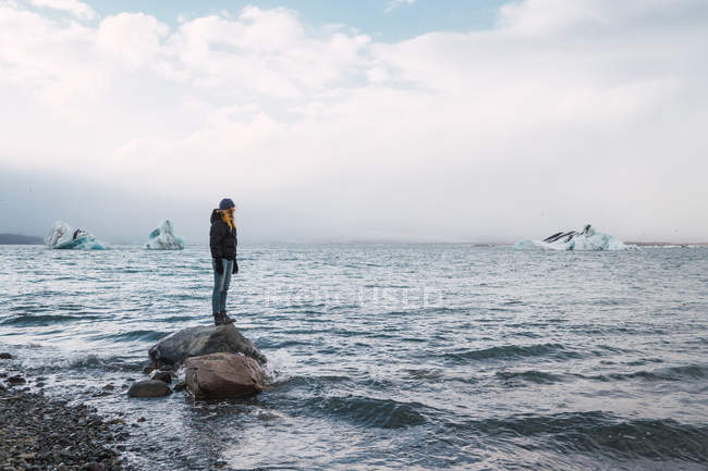 Girl standing on rock in sea and looking at view — Stock Photo