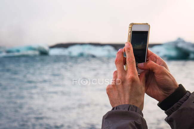 Crop man taking photo on cold beach - foto de stock