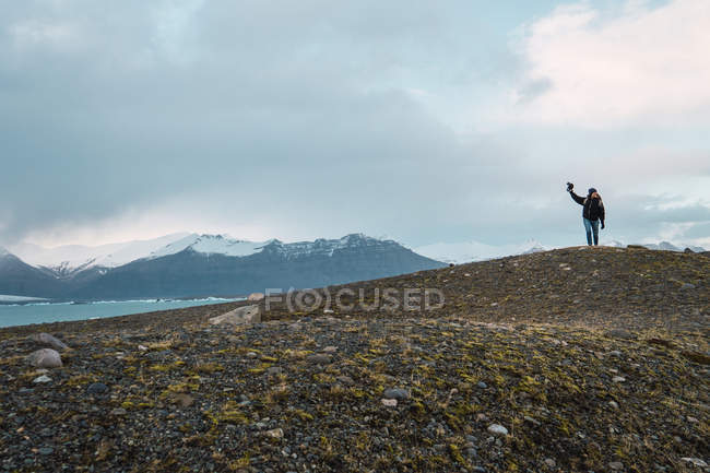 Woman with camera walking in mountains at sea — Stock Photo