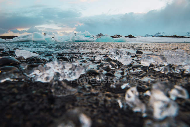 Пейзаж береговой линии с фрагментами ледника Йокульсарлон на фоне скалистых гор — стоковое фото