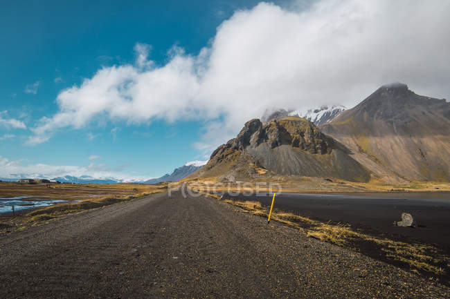 Landscape of remote mountains and road and blue sky with clouds, Iceland — Stock Photo