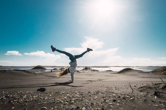 Happy female tourist doing handstand in nature — Stock Photo